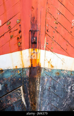 Close up de proue de vieux navire abandonné ancrés sur la terre ferme. Peinture rouge et bleu, ligne plimsoll et fer rouillé. Fortement texturé et patiné. Banque D'Images