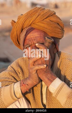 Ancien indien dans un turban fumant une pipe au bétail Nagaur juste au Rajasthan, en Inde. Banque D'Images