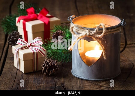 Décoration romantique shabby chic Lanterne en étain avec festive des cadeaux de Noël et branches de sapin rustique en bois sombre contre l'arrière-plan Banque D'Images