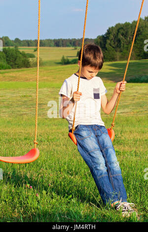 Sad lonely boy sitting on swing Banque D'Images