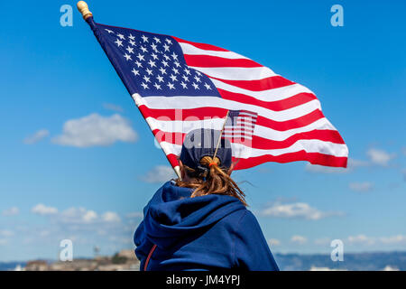 SAN FRANCISCO-Le 25 septembre 2013 : une fille avec un drapeau américain coincé dans sa queue de vagues un grand indicateur après USA gagne l'America's Cup dans la course finale. Banque D'Images