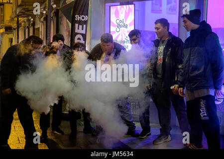 Un groupe d'hommes, la création de nuages de vapeur pendant l'utilisation de cigarettes électroniques england uk Banque D'Images