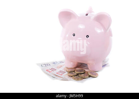 Concept d'économie d'argent en espèces avec petit mignon pink piggy bank et quelques pièces et billets en GBP, close-up isolated on white background with copy space Banque D'Images