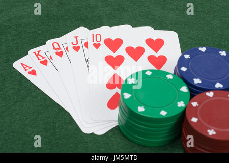 Passage vue rapprochée de la pile des jetons de poker de couleur rouge, vert et bleu en jouant cartes sur table couverte d'un feutre vert Banque D'Images