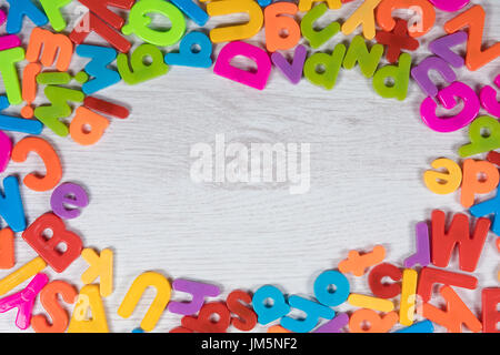 Châssis de couleur arc-en-ciel coloré de lettres de l'alphabet avec copie espace central sur bois peint blanc pour l'apprentissage, l'enseignement et l'éducation concepts Banque D'Images