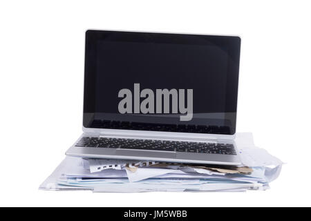 Pile de papiers en désordre avec un ordinateur portable en équilibre sur le haut dans un concept de travail inachevé et délais over white Banque D'Images