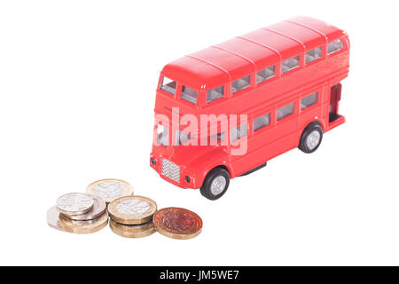Pile de UK L'argent comptant dans les coins avec un modèle de bus à impériale rouge dans un concept du coût des transports publics et des déplacements Banque D'Images