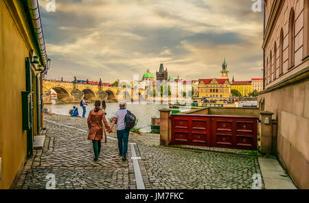 Un couple se dirige vers la rivière et le Pont Charles à Prague sous un ciel couvert journée d'automne Banque D'Images