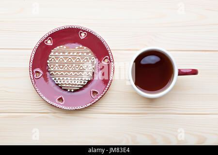 Gingerbread cookie sur la plaque rouge et le thé chaud sur la table en bois. Banque D'Images