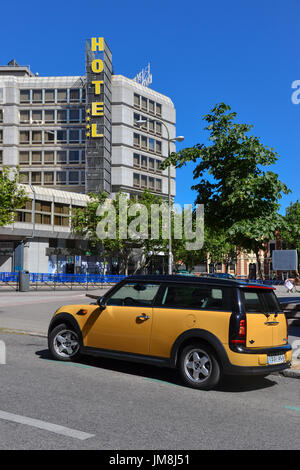 Hôtel avec logo jaune avec une Mini Cooper jaune garée en face d'elle, à Madrid, Espagne. Banque D'Images