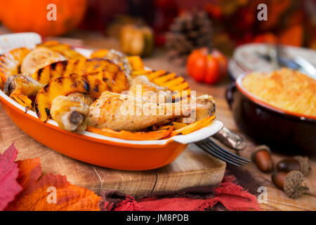 Une cocotte au four poulet rôti et de citrouille grillées sur une table rustique avec des décorations d'automne. Banque D'Images