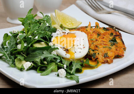 Idée brunch. Avec les épinards pochés oeufs potiron crêpes et garnir de roquette, d'avocat, les feuilles de menthe, et de la ricotta Banque D'Images