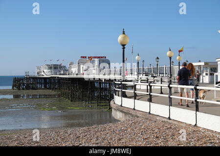 Un couple voung avec une promenade en chien le long de la jetée de Worthing, West Sussex, Royaume-Uni Banque D'Images