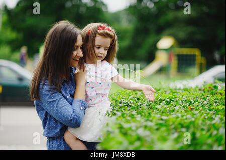 Jeune mère de promenades dans le parc avec la petite fille. La femme tient le bébé sur les mains. Elle appuie doucement à elle-même la fille. Le woman hold Banque D'Images