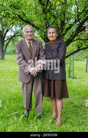 Plus de 80 ans mignon vieux couple posant pour un portrait dans leur jardin. Concept de l'amour pour toujours. Banque D'Images