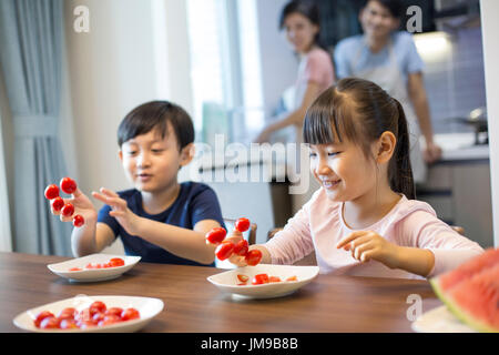 Frères et sœurs chinois heureux et tomates cerises Banque D'Images