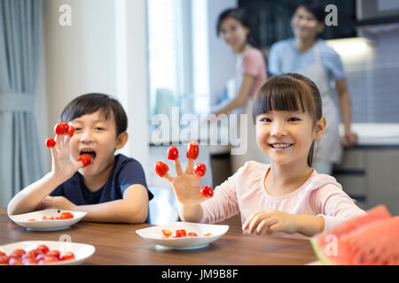 Frères et sœurs chinois heureux et tomates cerises Banque D'Images