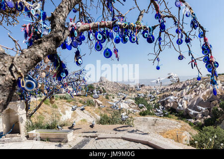 Mauvais Œil des perles sur arbre et cheminées de fées sur fond de ciel bleu dans la vallée de Guvercinlik, Goreme,Turquie.Branches du vieil arbre décoré de t Banque D'Images