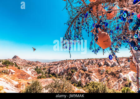 Mauvais Œil des perles sur arbre et cheminées de fées sur fond de ciel bleu dans la vallée de Guvercinlik, Goreme,Turquie.Branches du vieil arbre décoré de t Banque D'Images