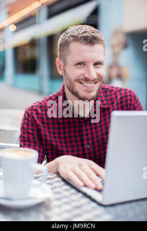 Portrait of Young Man at Outdoor Cafe Working On Laptop Banque D'Images