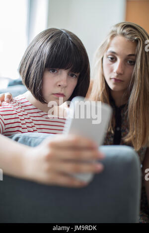 Teenage Girl with Friend Intimidé par message texte Banque D'Images