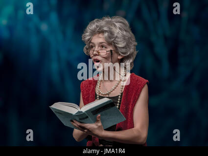 En tant que grand-mère fille déguisée lit un livre à l'audiance. Banque D'Images