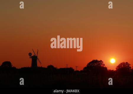 Great Bircham, UK. Le 25 juillet, 2017. Le ciel devient orange comme le soleil se couche derrière Bircham windmill à Norfolk. Bircham Mill a été construit en 1846, mais dans les années 20, les voiles ont été supprimés et la tour a été abandonné, mais maintenant c'est un moulin entièrement restauré et de travail Bircham windmill in Great Bircham, Norfolk le 25 juillet 2017 Crédit : Paul Marriott/Alamy Live News Banque D'Images