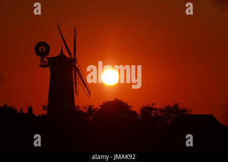 Great Bircham, UK. Le 25 juillet, 2017. Le ciel devient orange comme le soleil se couche derrière Bircham windmill à Norfolk. Bircham Mill a été construit en 1846, mais dans les années 20, les voiles ont été supprimés et la tour a été abandonné, mais maintenant c'est un moulin entièrement restauré et de travail Bircham windmill in Great Bircham, Norfolk le 25 juillet 2017 Crédit : Paul Marriott/Alamy Live News Banque D'Images