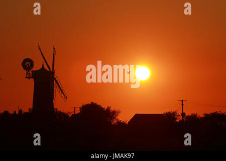 Great Bircham, UK. Le 25 juillet, 2017. Le ciel devient orange comme le soleil se couche derrière Bircham windmill à Norfolk. Bircham Mill a été construit en 1846, mais dans les années 20, les voiles ont été supprimés et la tour a été abandonné, mais maintenant c'est un moulin entièrement restauré et de travail Bircham windmill in Great Bircham, Norfolk le 25 juillet 2017 Crédit : Paul Marriott/Alamy Live News Banque D'Images