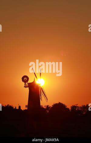 Great Bircham, UK. Le 25 juillet, 2017. Le ciel devient orange comme le soleil se couche derrière Bircham windmill à Norfolk. Bircham Mill a été construit en 1846, mais dans les années 20, les voiles ont été supprimés et la tour a été abandonné, mais maintenant c'est un moulin entièrement restauré et de travail Bircham windmill in Great Bircham, Norfolk le 25 juillet 2017 Crédit : Paul Marriott/Alamy Live News Banque D'Images