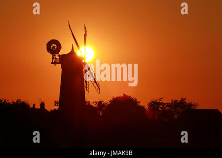 Great Bircham, UK. Le 25 juillet, 2017. Le ciel devient orange comme le soleil se couche derrière Bircham windmill à Norfolk. Bircham Mill a été construit en 1846, mais dans les années 20, les voiles ont été supprimés et la tour a été abandonné, mais maintenant c'est un moulin entièrement restauré et de travail Bircham windmill in Great Bircham, Norfolk le 25 juillet 2017 Crédit : Paul Marriott/Alamy Live News Banque D'Images