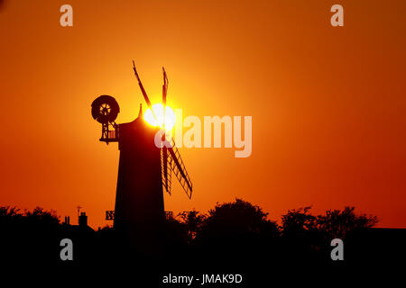 Great Bircham, UK. Le 25 juillet, 2017. Le ciel devient orange comme le soleil se couche derrière Bircham windmill à Norfolk. Bircham Mill a été construit en 1846, mais dans les années 20, les voiles ont été supprimés et la tour a été abandonné, mais maintenant c'est un moulin entièrement restauré et de travail Bircham windmill in Great Bircham, Norfolk le 25 juillet 2017 Crédit : Paul Marriott/Alamy Live News Banque D'Images