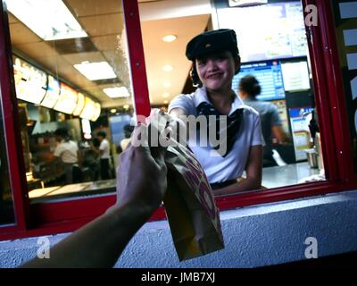 ANTIPOLO CITY, PHILIPPINES - le 17 juillet 2017 : une chaîne de restauration rapide travailleur donne un client un produit acheté à un drive thru. Banque D'Images