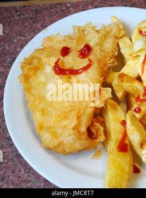 Mini repas de poisson et frites avec un smiley dessiné à la sauce tomate Banque D'Images