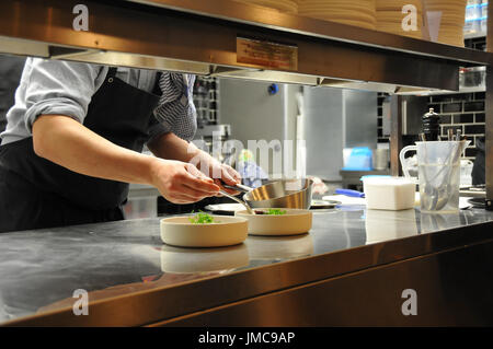 La préparation de plats de chef de cuisine au restaurant, pas de visage seulement mains Banque D'Images