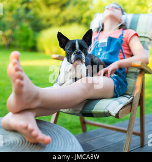 Chien et adolescente se reposant dans le jardin - sweet boston terrier chiot sur les genoux de sa dame Banque D'Images