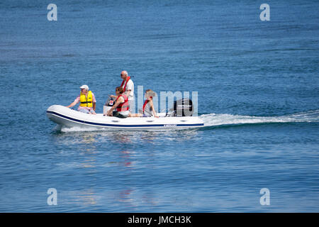 Un petit groupe de deux hommes et deux femmes voyageant dans un petit bateau gonflable rigide sur une journée ensoleillée Banque D'Images