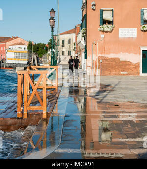 Grande flaque qui reflète les gens qui marchent le long du Canal de la Giudecca à Venise, Italie Banque D'Images