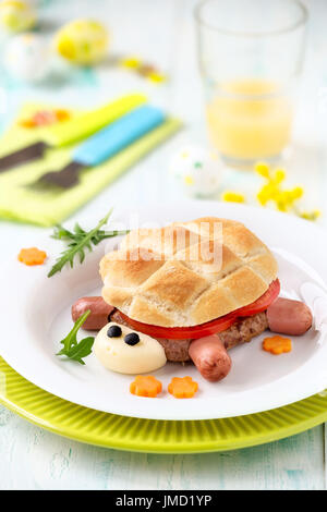 Fun food for kids - mignon en forme de tortue hamburger de viande pattie, tranches de tomate fraîche et de pain avec decoraions de Pâques à l'arrière-plan Banque D'Images