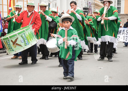 Un petit garçon bolivien en costumes traditionnels jouant la flûte durant la célébration de la journée de la fondation de l'État plurinational, La Paz, Bolivie Banque D'Images