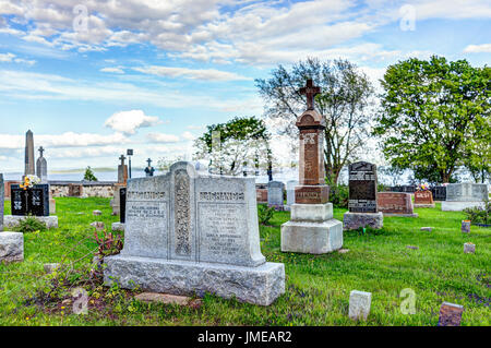 L'ÎLE D'Orléans, Canada - 1 juin 2017 : cimetière de l'église Saint-Jean avec des pierres tombales en pierre et ciel bleu en été Banque D'Images