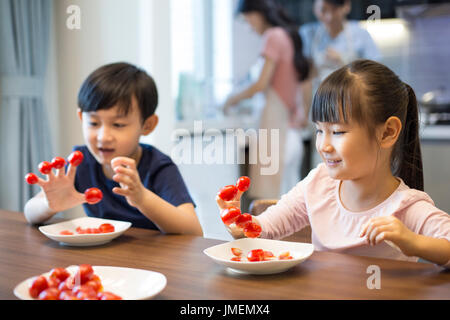 Frères et sœurs chinois heureux et tomates cerises Banque D'Images