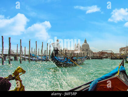Belle journée sur le grand canal prises à partir d'une gondole gondole avec un autre à l'avant avec un gondolier et direction des éclaboussures d'eau et d'une cathédrale Banque D'Images