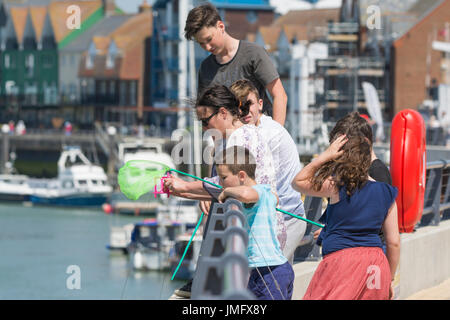 La pêche du crabe. Les jeunes la pêche de crabes par la rivière à Littlehampton, West Sussex, Angleterre, Royaume-Uni. Banque D'Images