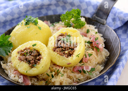 Boulettes de pommes de terre farcies à la viande hachée et servi avec de la choucroute et du bacon dans une poêle de fer Banque D'Images