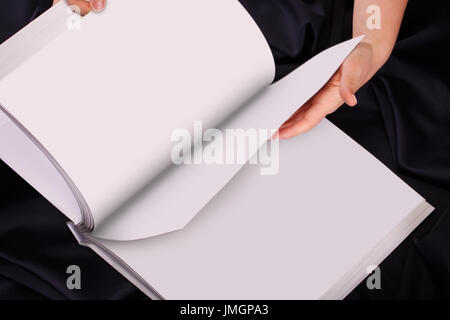 Une femme ou une femme deux mains tiennent un livre vierge ou vide ou remarque, journal ou propagation de déplier, vue du dessus, studio. Banque D'Images