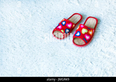 Womens rouge Chaussons avec des coeurs sur tapis fibreux blanc. Accueil féminin. photo with copy space Banque D'Images