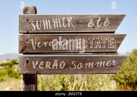 Libre d'un panneau en bois rustique dans un paysage naturel avec le mot de l'été rédigé en anglais, français, espagnol, italien, portugais et allemand, je Banque D'Images