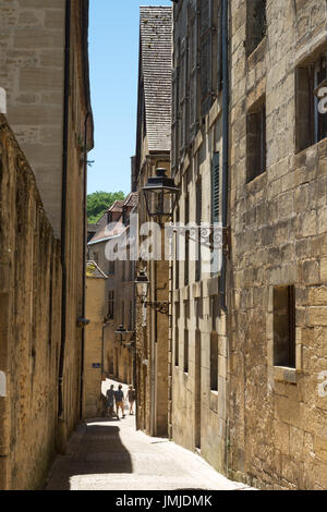 Trois personnes à pied dans une rue étroite à Sarlat-la-Canéda, Dordogne, France Banque D'Images