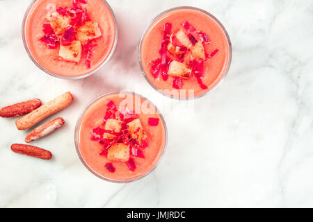 Une photo d'un salmorejo, soupe froide espagnole traditionnelle, servie dans des verres avec des bâtonnets de pain, garnie de jambon et croûtons, tourné par le haut avec un Banque D'Images